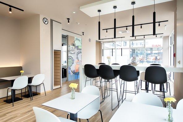 Moderner Fr&uuml;hst&uuml;cksbereich mit wei&szlig;en Tischen, schwarzen St&uuml;hlen und gelben Blumen in Vasen. Gro&szlig;e Fenster lassen viel Licht herein., &copy; B&B Hotel Stuttgart-Neckarhafen