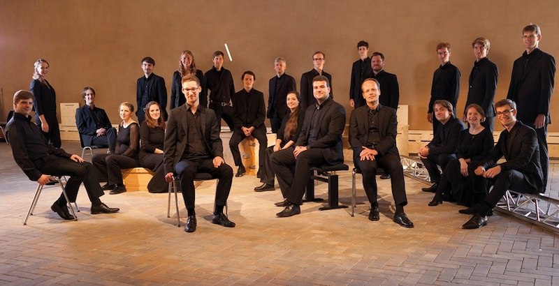 Eine Gruppe von Menschen in schwarzer Kleidung sitzt und steht in einem Raum mit Ziegelboden. Sie wirken professionell und konzentriert., © Stiftsmusik Stuttgart Eine Gruppe von Menschen in schwarzer Kleidung sitzt und steht in einem Raum mit Ziegelboden. Sie wirken professionell und konzentriert., © Stiftsmusik Stuttgart