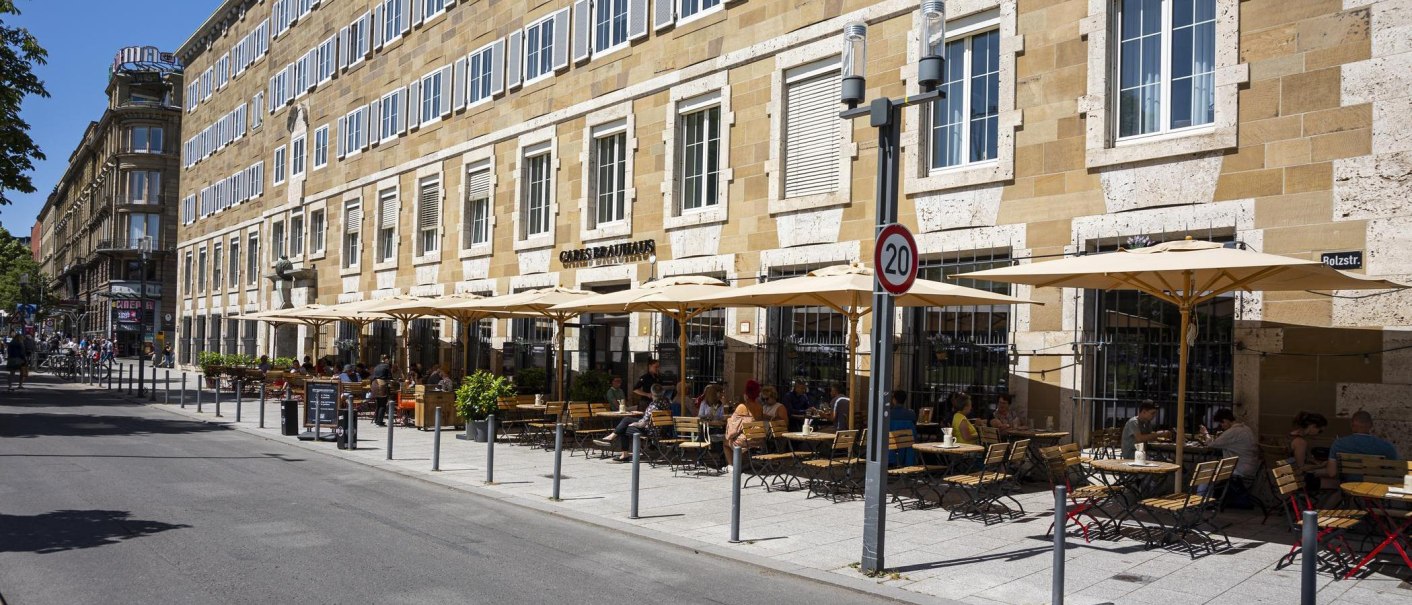 Carls Brauhaus with street café, parasols and guests on a busy street in sunny weather., © SMG Stuttgart Marketing GmbH - Sarah Schmid