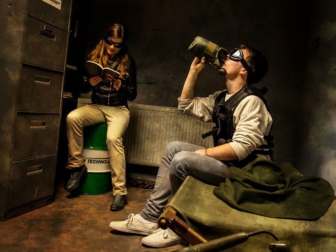 Two people in a room, one sitting on a barrel and reading, the other drinking from a bottle. Both are wearing safety goggles., © ExitGames Stuttgart Two people in a room, one sitting on a barrel and reading, the other drinking from a bottle. Both are wearing safety goggles., © ExitGames Stuttgart