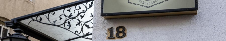 A sign reading 'Hanky Panky Cocktail & co' hangs on a wall next to house number 18. A lantern and a decorative canopy are visible., © Stuttgart-Marketing GmbH, Sarah Schmid A sign reading 'Hanky Panky Cocktail & co' hangs on a wall next to house number 18. A lantern and a decorative canopy are visible., © Stuttgart-Marketing GmbH, Sarah Schmid