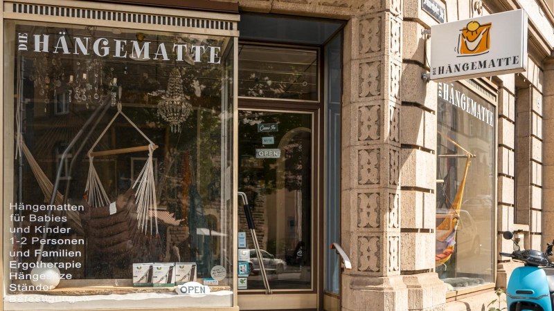 Store 'Die Hängematte' in Stuttgart with display window showing hammocks and accessories. A blue scooter is parked in front of it., © SMG, Sarah Schmid