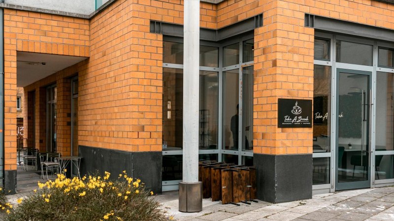 Eingang des Caf&eacute;s mit gelben Backsteinw&auml;nden. Gelbe Blumen im Vordergrund., &copy; Stuttgart-Marketing GmbH, Sarah Schmid