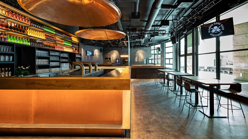 Modern caf&eacute; with bar, illuminated shelves full of bottles, glasses and seating areas. Large windows let in plenty of light., &copy; Maks Richter