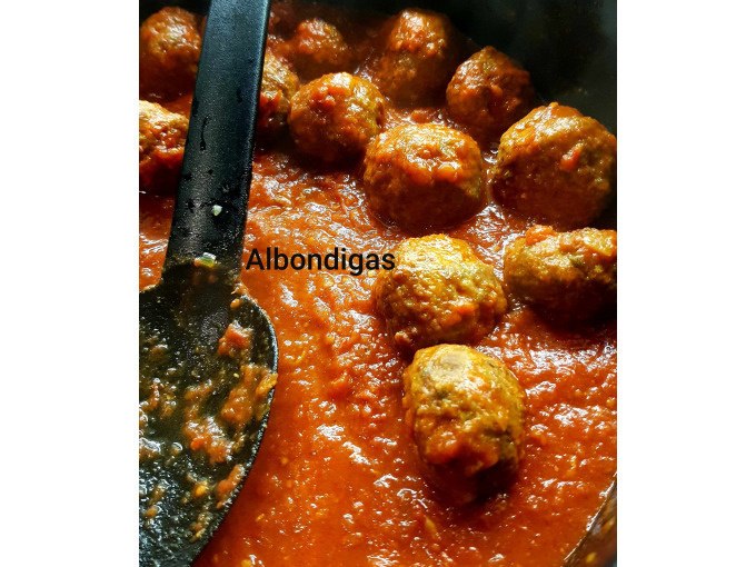 Meatballs in tomato sauce, known as 'albondigas', with a black wooden spoon in a pan., &copy; Kultweine-Kochwelten-Kunst&uuml;cke - Kochschule Sonja Lenz