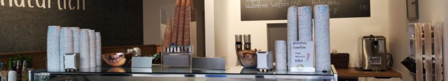 Ice cream parlor with ice cream counter, various types of ice cream, menu board and modern lighting. 'Naturally' lettering on the wall., &copy; Joannis Nakos