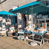 A store in the south of Stuttgart with blue parasols. Fabric items and decorations are displayed on tables and chairs outside., © Cosima Chiton, Stuttgart A store in the south of Stuttgart with blue parasols. Fabric items and decorations are displayed on tables and chairs outside., © Cosima Chiton, Stuttgart