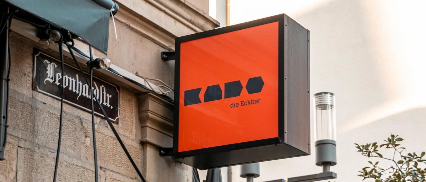 Ein leuchtend oranges Schild mit der Aufschrift 'Kado die Eckbar' h&auml;ngt an einer Hauswand in der Leonhardstra&szlig;e., &copy; Stuttgart-Marketing GmbH, Sarah Schmid