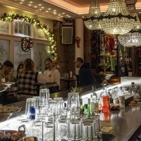 Festlich dekorierte Bar mit Kronleuchtern, Gläsern und Getränken auf der Theke. Gäste sitzen und unterhalten sich in gemütlicher Atmosphäre., © Stuttgart Marketing GmbH, Sarah Schmid Festlich dekorierte Bar mit Kronleuchtern, Gläsern und Getränken auf der Theke. Gäste sitzen und unterhalten sich in gemütlicher Atmosphäre., © Stuttgart Marketing GmbH, Sarah Schmid