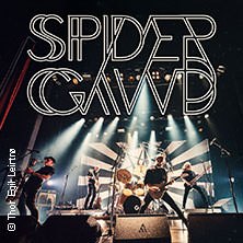 Die Band Spidergawd performt auf einer B&uuml;hne mit Lichteffekten. Im Hintergrund ist das Bandlogo gro&szlig; zu sehen., &copy; links im Bild