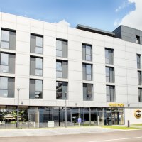 Modernes Hotelgebäude mit Glasfassade, Beschilderung 'Hotel' und 'Rezeption', umgeben von Grünflächen., © B&B Hotel Stuttgart-Neckarhafen Modernes Hotelgebäude mit Glasfassade, Beschilderung 'Hotel' und 'Rezeption', umgeben von Grünflächen., © B&B Hotel Stuttgart-Neckarhafen