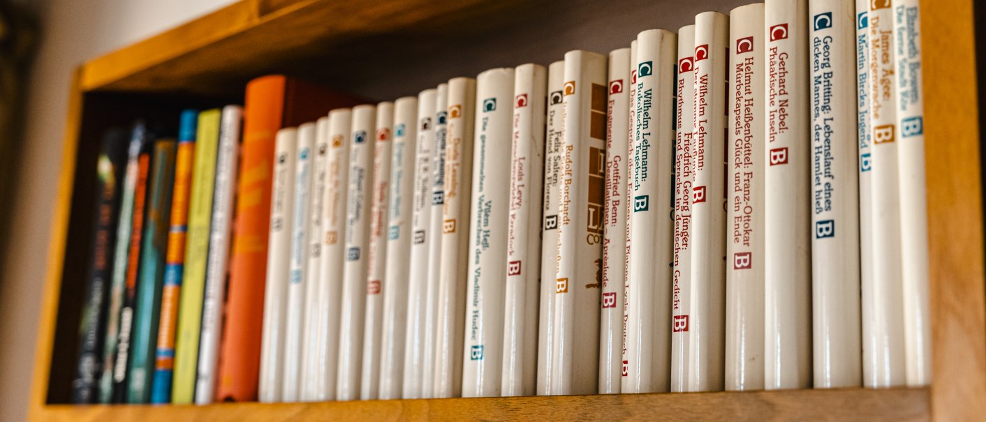 Ein Holzregal mit einer Reihe von Büchern in weißen Einbänden, ordentlich nebeneinander aufgereiht., © SMG Stuttgart Marketing GmbH - Sarah Schmid