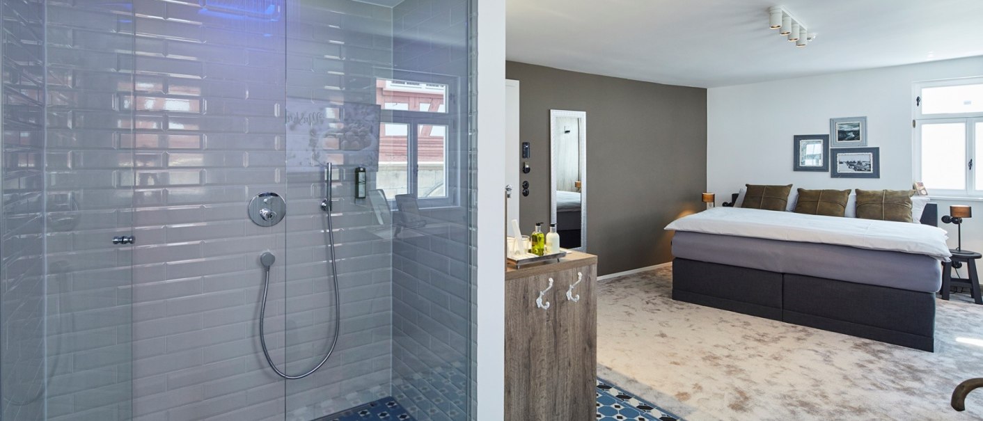 Modernes Zimmer mit offener Dusche, blauer Beleuchtung, Doppelbett und stilvollen Dekorationen. Teppichboden und Fliesen im Duschbereich., &copy; Hotel Restaurant Bachofer
