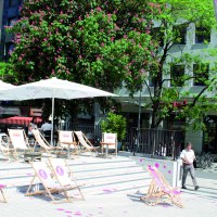 Sunny outdoor area with sun loungers and parasols in front of a building. Blossoming trees and passers-by in the background., &copy; &copy; Stuttgart-Marketing GmbH (SMG)