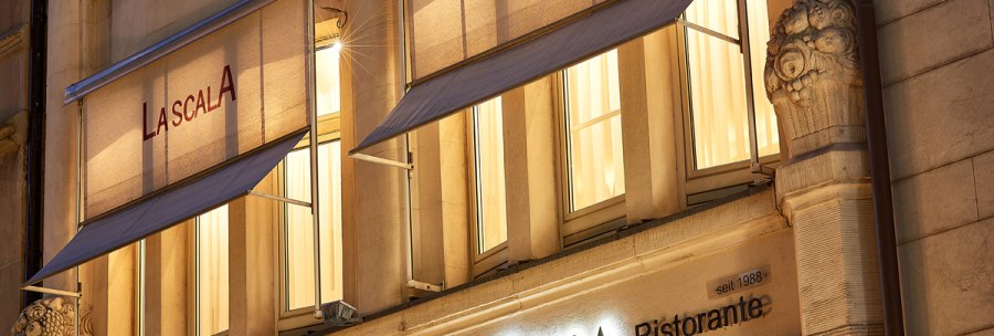 Beleuchtete Fassade des Restaurants La Scala in Stuttgart mit Markisen und dekorativen Säulen bei Nacht., © La Scala