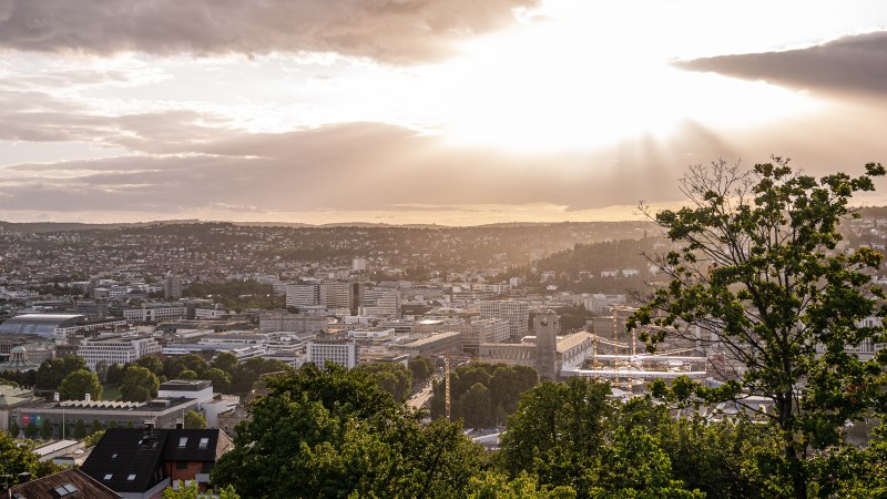 Blick von der Uhlandsh&ouml;he auf Stuttgart bei Sonnenuntergang. Die Stadt liegt unter einem dramatischen Himmel mit Sonnenstrahlen und Wolken., &copy; Christine Garcia, Urban Trickytine