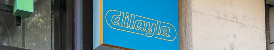 Blue sign with yellow lettering 'dilayla' on a building wall, next to it a green arrow., © Stuttgart Marketing GmbH, Sarah Schmid