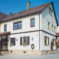 Two-storey building with a yellow and white façade and red roof tiles. A VdW banner stands in front of it. Clear blue sky in the background., © Weinstube Jägerhof