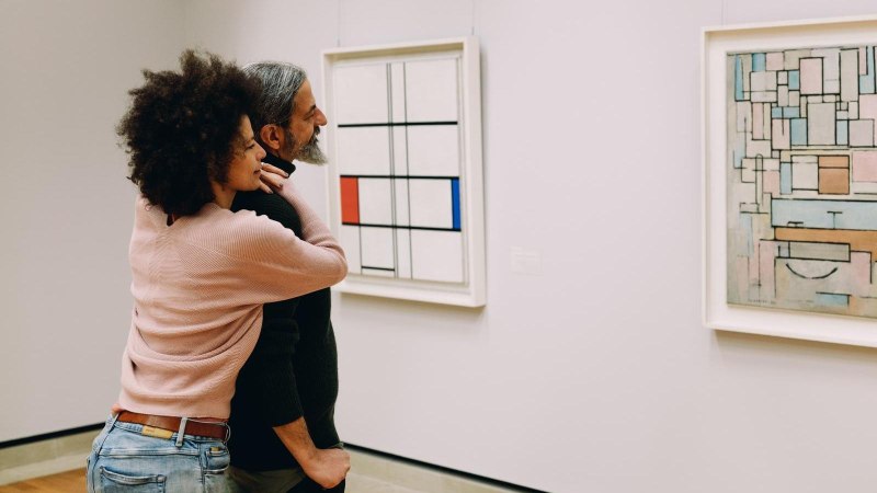 Ein Paar betrachtet zwei abstrakte Gemälde in einer Kunstgalerie. Die Gemälde zeigen geometrische Formen und Linien in verschiedenen Farben., © Stuttgart-Marketing GmbH, Alwin Maigler Ein Paar betrachtet zwei abstrakte Gemälde in einer Kunstgalerie. Die Gemälde zeigen geometrische Formen und Linien in verschiedenen Farben., © Stuttgart-Marketing GmbH, Alwin Maigler