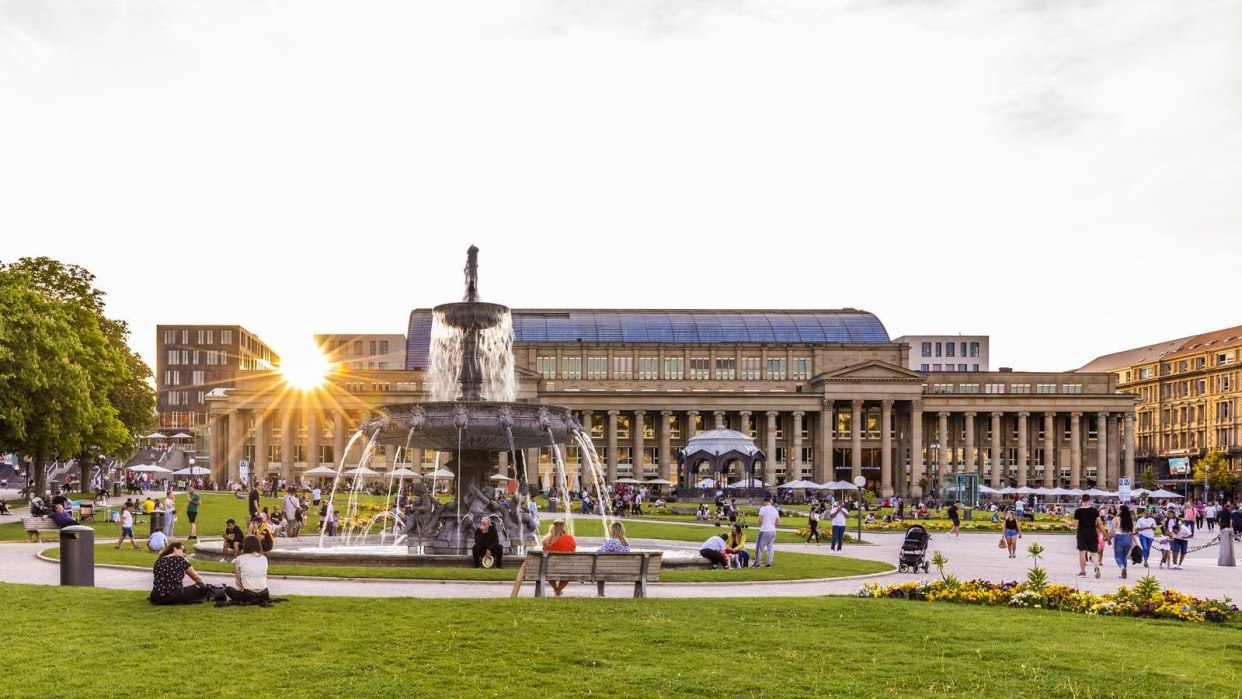 Schlossplatz in Stuttgart at sunset, people relaxing on the lawn, the Königsbau and a fountain in the background., © Stuttgart-Marketing GmbH, Werner Dieterich Schlossplatz in Stuttgart at sunset, people relaxing on the lawn, the Königsbau and a fountain in the background., © Stuttgart-Marketing GmbH, Werner Dieterich