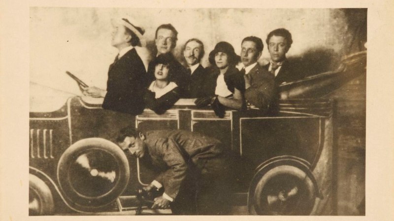 A group of people pose in a painted car at a funfair. The scene appears humorous and staged., &copy; Anonym, Jahrmarkt auf dem Montmartre, 1923, Staatsgalerie Stuttgart, Graphische Sammlung, erworben 2025 aus Mitteln der Museumsstiftung Baden-W&uuml;rttemberg, Sammlung Dietmar Siegert