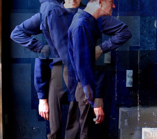 Ein Mann in blauer Kleidung steht mehrfach überlagert vor einer dunklen Wand, was einen surrealen Effekt erzeugt., © Wilhelma Theater Ein Mann in blauer Kleidung steht mehrfach überlagert vor einer dunklen Wand, was einen surrealen Effekt erzeugt., © Wilhelma Theater