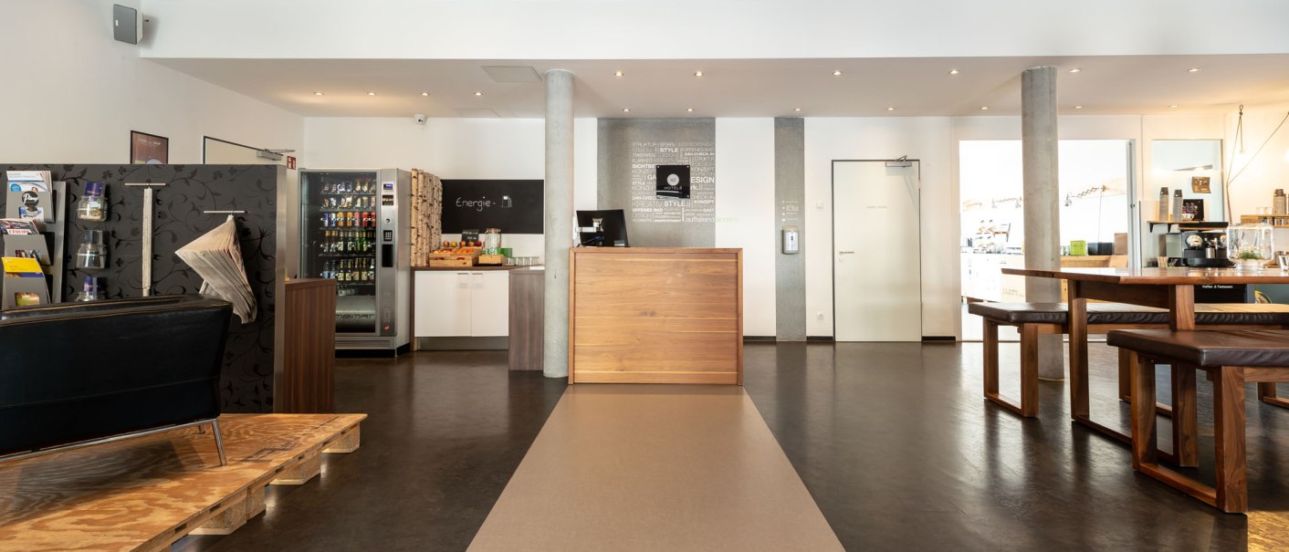 Modern lobby with wooden reception desk, seating area, vending machines and bright lighting. Inviting atmosphere with minimalist furnishings., &copy; a2 HOTELS Plochingen