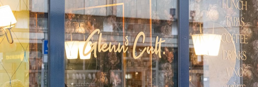Fensterscheibe eines Caf&eacute;s mit dem Schriftzug 'Glenn's Cult' und Angeboten wie Aperitivo, Lunch, Tapas, Coffee, Drinks, Vino, Spirits., &copy; SMG, Sarah Schmid