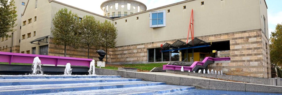 The Haus der Geschichte features modern architecture with a fountain in the foreground. Trees line the building, which impresses with its clear lines and colors., © hdgbw