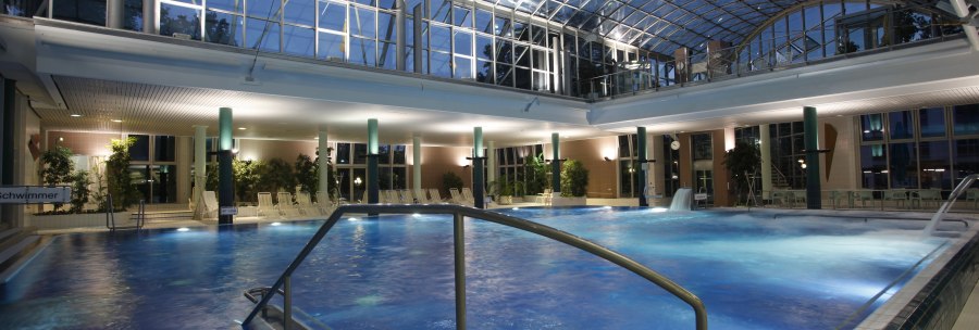 Beleuchtetes Schwimmbad mit Glasdach und Pflanzen. Der Pool ist von Liegest&uuml;hlen umgeben, die Atmosph&auml;re ist ruhig und entspannend., &copy; Stuttgarter B&auml;der