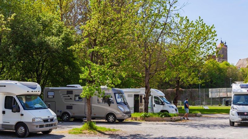 Motorhome site in Besigheim with several motorhomes under green trees, a church visible in the background., &copy; Boris Lehner