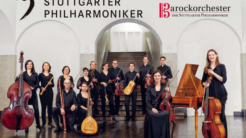 The baroque orchestra of the Stuttgart Philharmonic poses with instruments in front of a staircase. The musicians wear black clothing., &copy; Barockorchester der Stuttgarter Philharmoniker