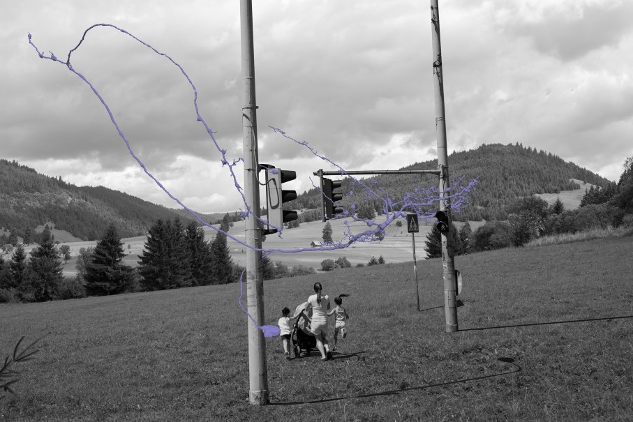 Schwarz-weißes Bild einer Landschaft mit Ampeln und lila Linien. Eine Person mit Kindern und Kinderwagen im Vordergrund, Hügel im Hintergrund., © balazs csizik