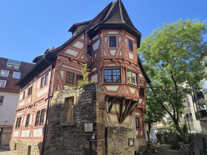 Ein historisches Fachwerkhaus mit roten Balken und steilem Dach in einer Altstadt. Ein Baum und blauer Himmel im Hintergrund., &copy; Cool-Tours StattReisen