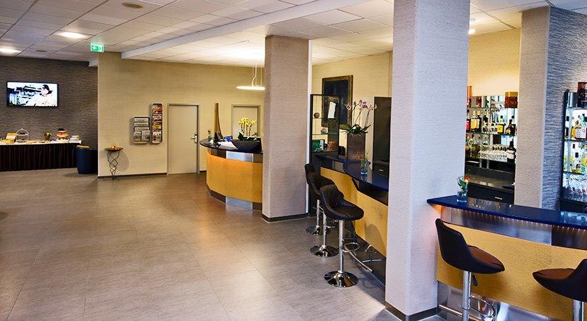 A modern lobby with a bar, a counter, and bar stools. In the background, there is a buffet and a TV on the wall., &copy; bonjour Hotelbetriebs GmbH