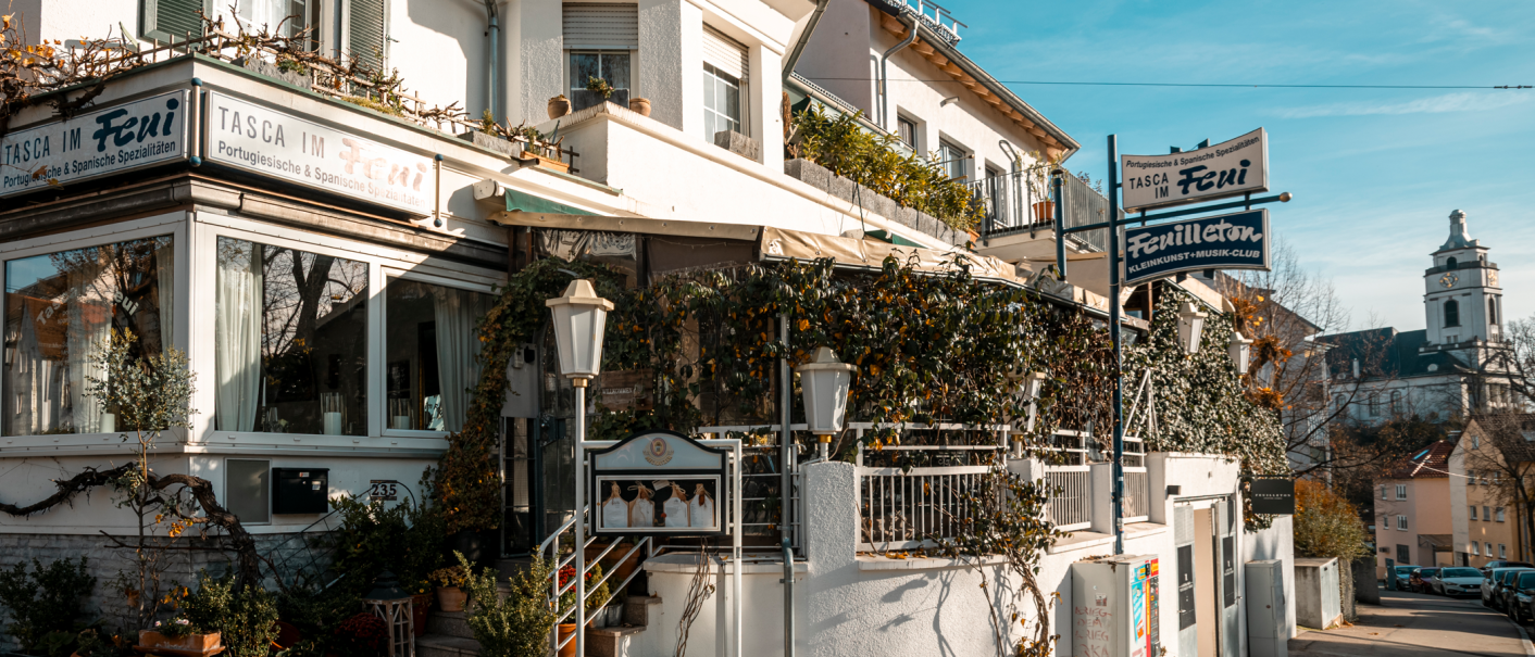 Ein Restaurant mit dem Namen 'Tasca im Feui', das portugiesische und spanische Spezialit&auml;ten anbietet. Daneben ein Schild f&uuml;r 'Feuilleton', einen Kleinkunst- und Musikclub., &copy; Stuttgart-Marketing GmbH, Sarah Schmid