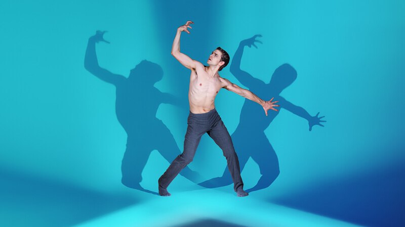 Ein T&auml;nzer in einer dynamischen Pose vor einem blauen Hintergrund. Mehrere Schatten verst&auml;rken den dramatischen Effekt., &copy; W&uuml;rttembergische Staatstheater Stuttgart