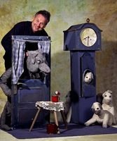 Ein Puppenspieler zeigt eine Szene aus 'Der Wolf und die sieben Geißlein' mit Puppen und Requisiten wie einer Uhr und einem Tisch., © FITZ Das Theater animierter Formen Ein Puppenspieler zeigt eine Szene aus 'Der Wolf und die sieben Geißlein' mit Puppen und Requisiten wie einer Uhr und einem Tisch., © FITZ Das Theater animierter Formen