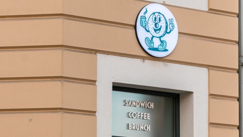 Ein Bagel-Logo mit Kaffeebecher und Peace-Zeichen an einer Gebäudewand. Darunter steht 'Sandwich Coffee Brunch'., © Stuttgart-Marketing GmbH, Sarah Schmid Ein Bagel-Logo mit Kaffeebecher und Peace-Zeichen an einer Gebäudewand. Darunter steht 'Sandwich Coffee Brunch'., © Stuttgart-Marketing GmbH, Sarah Schmid