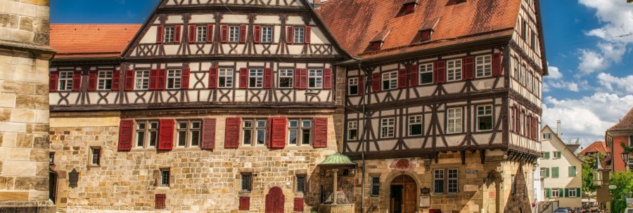 Historic half-timbered house with red shutters and stone details in Esslingen, surrounded by cobblestones and passers-by., &copy; KESSLER Sekt GmbH & Co. KG