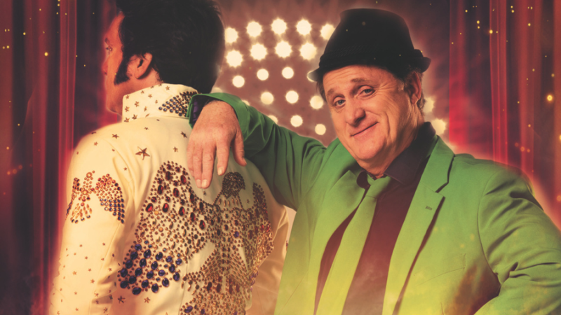 A man in a green suit leans casually against an Elvis impersonator. Stage lights can be seen in the background, creating a concert atmosphere., &copy; Friedrichsbau Variet&eacute;