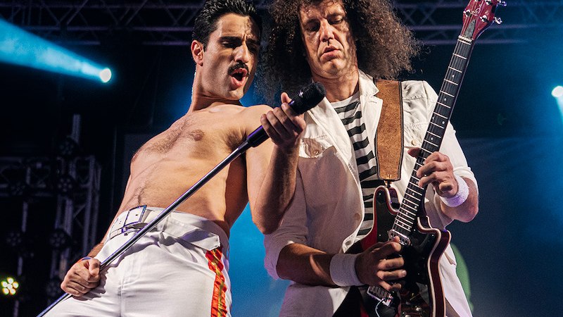 Zwei Musiker auf der Bühne: Einer singt leidenschaftlich ins Mikrofon, der andere spielt Gitarre. Sie tragen weiße Outfits und sind in Aktion vertieft., © C2 Concerts GmbH Zwei Musiker auf der Bühne: Einer singt leidenschaftlich ins Mikrofon, der andere spielt Gitarre. Sie tragen weiße Outfits und sind in Aktion vertieft., © C2 Concerts GmbH