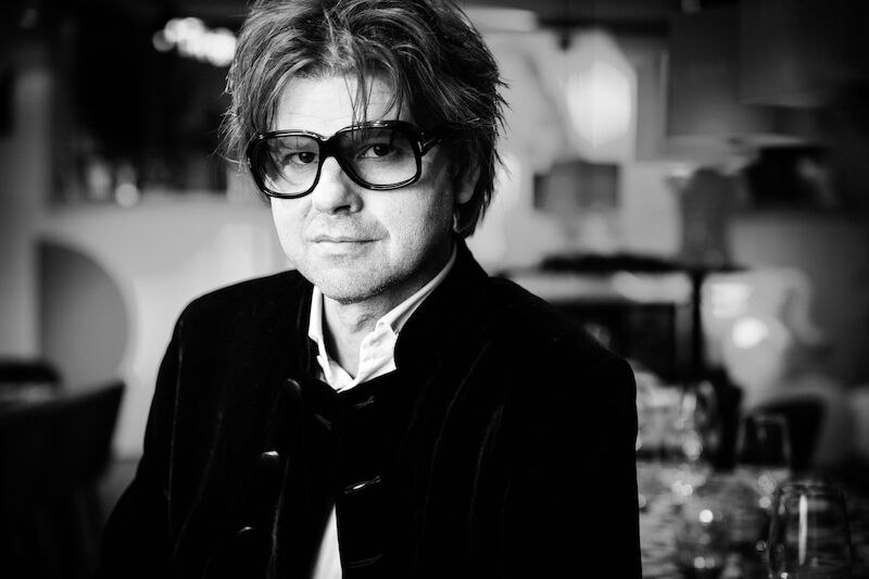 Black and white portrait of a man with large glasses and medium-length hair in an elegant setting., &copy; SWR Big Band