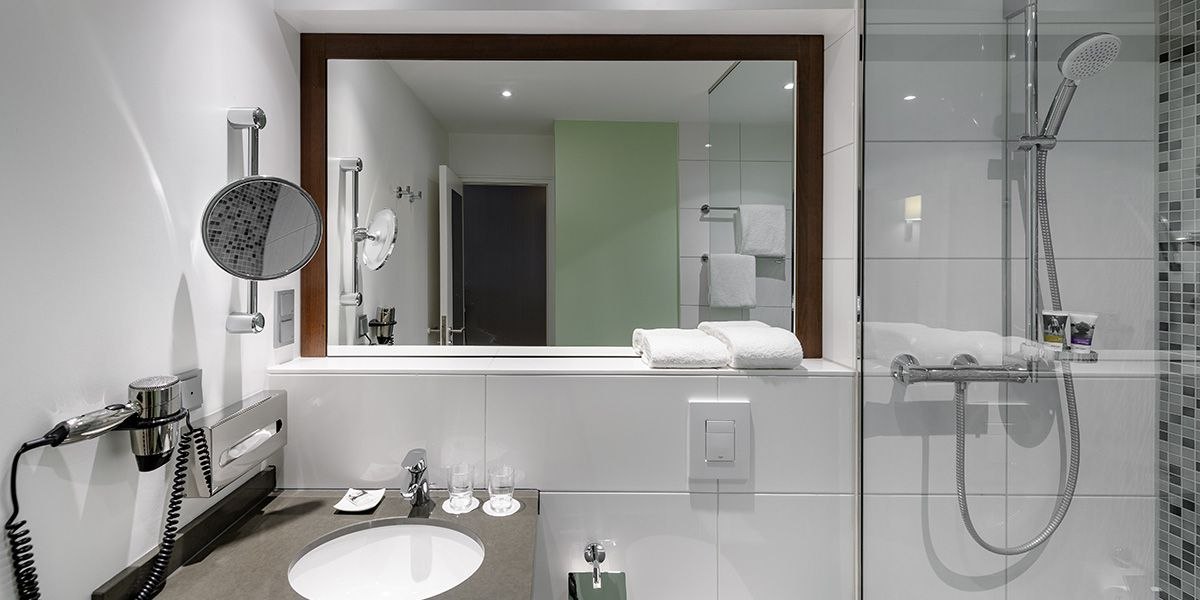 Modernes Badezimmer mit großem Spiegel, Waschbecken, Handtüchern und Dusche. Ein Föhn und ein Vergrößerungsspiegel sind an der Wand angebracht., © Mercure Hotel Stuttgart Sindelfingen an der Messe Modernes Badezimmer mit großem Spiegel, Waschbecken, Handtüchern und Dusche. Ein Föhn und ein Vergrößerungsspiegel sind an der Wand angebracht., © Mercure Hotel Stuttgart Sindelfingen an der Messe