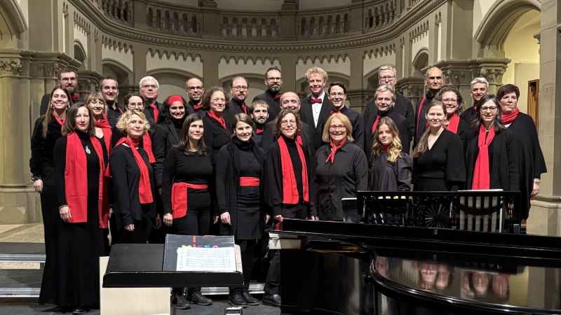 Der Junger Chor Stuttgart posiert in der Matthäuskirche. Die Mitglieder tragen schwarze Kleidung mit roten Schals und Accessoires., © Junger Chor Stuttgart e.V. Der Junger Chor Stuttgart posiert in der Matthäuskirche. Die Mitglieder tragen schwarze Kleidung mit roten Schals und Accessoires., © Junger Chor Stuttgart e.V.