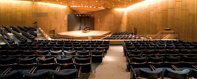 Ein leerer Konzertsaal mit Holzwänden, einer Bühne und einem Flügel. Die Sitzreihen sind dunkelblau gepolstert., © Württembergische Staatstheater Stuttgart