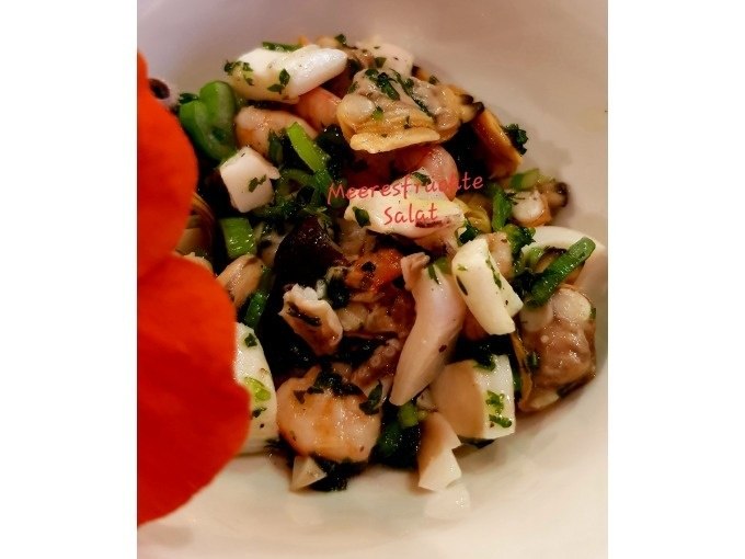 Seafood salad with herbs and vegetables in a bowl, decorated with an orange flower., &copy; Kultweine-Kochwelten-Kunst&uuml;cke - Kochschule Sonja Lenz