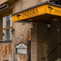 Restaurant Injeera with yellow sign and wooden fence, offers African cuisine. Exterior view with lanterns and plants., © SMG Stuttgart Marketing GmbH - Sarah Schmid Restaurant Injeera with yellow sign and wooden fence, offers African cuisine. Exterior view with lanterns and plants., © SMG Stuttgart Marketing GmbH - Sarah Schmid