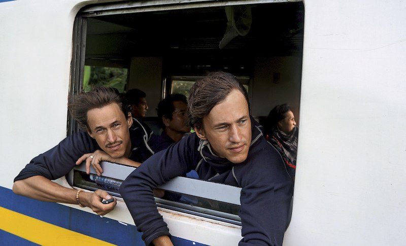 Zwei M&auml;nner lehnen sich aus einem Zugfenster und blicken nach drau&szlig;en. Im Hintergrund sind weitere Passagiere zu sehen., &copy; Theaterhaus Stuttgart e.V.