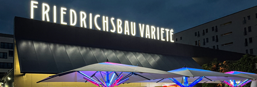 Abendliche Szene vor dem Friedrichsbau Varieté mit beleuchteten Sonnenschirmen und Menschen, die sich unterhalten und entspannen., © Friedrichsbau Varieté